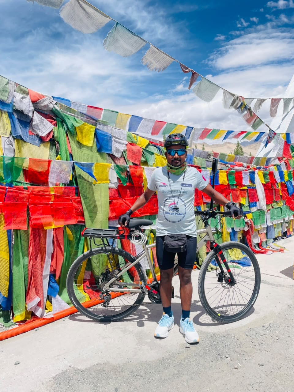 Shankar Kumar Thakur with his bicycle in Leh surrounded by Himalayan prayer flags